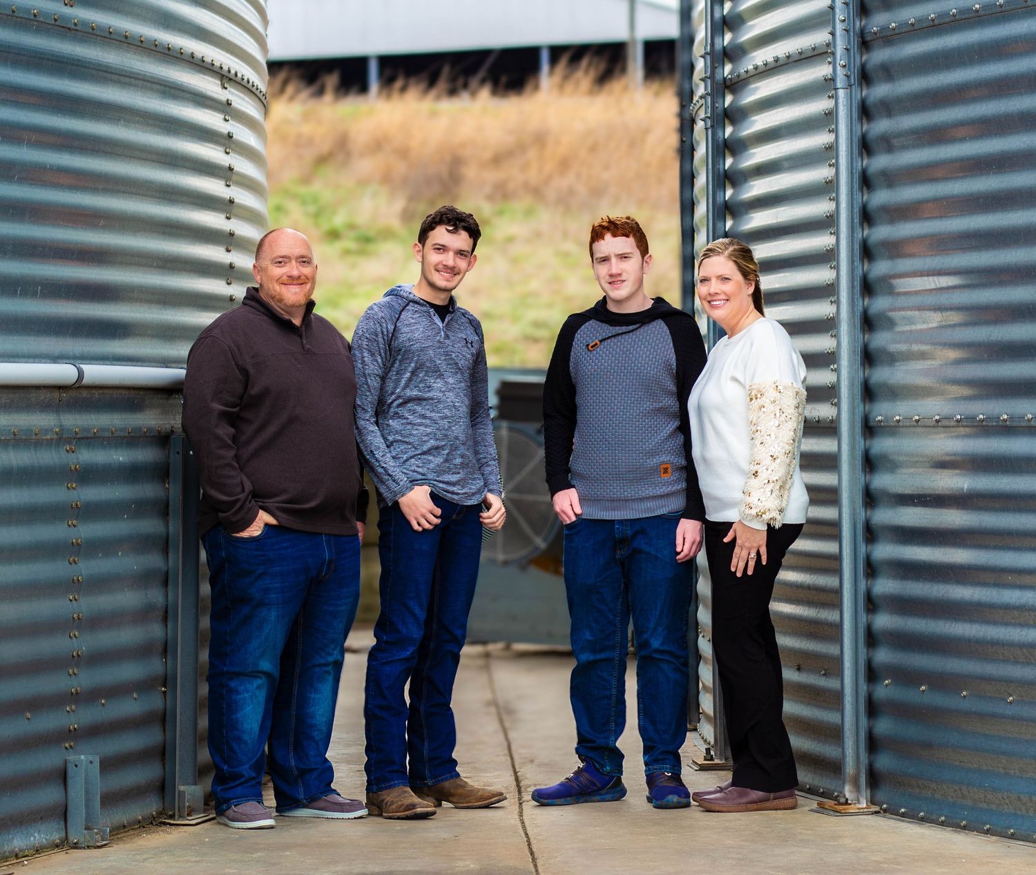Family of four posing together between metal grain bins