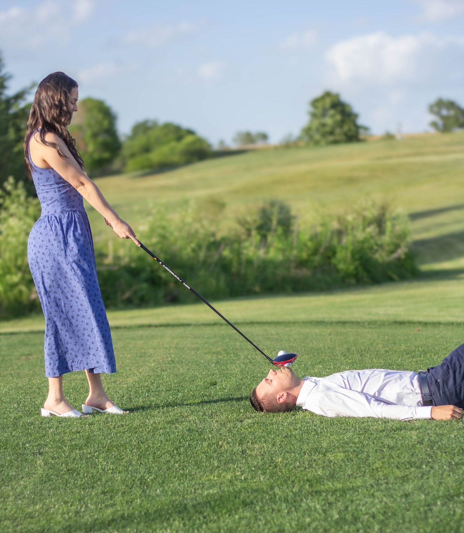 Bride pretending to hit golf ball off fiancé's mouth with a tee in it