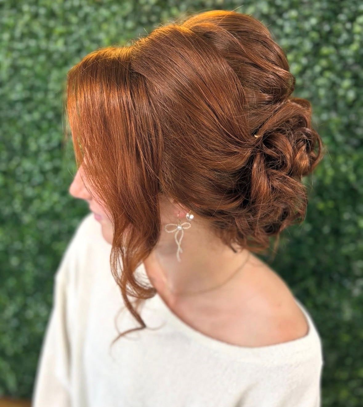 Romantic red bridal updo with soft face-framing curls.