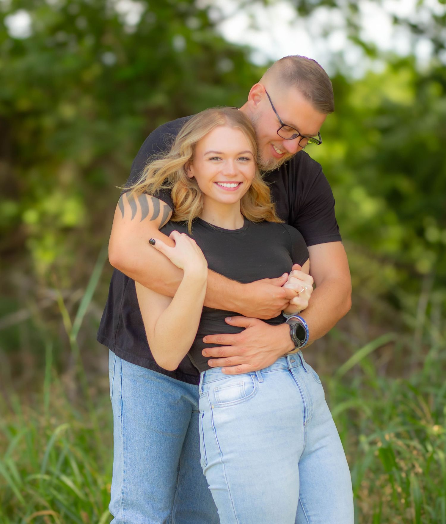Couple hugging during a relaxed outdoor engagement session.