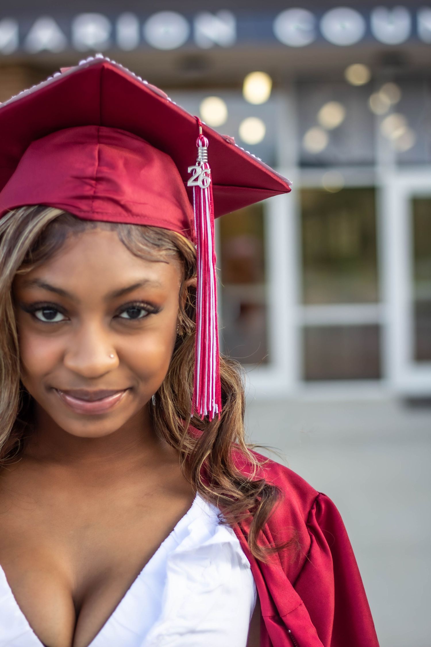 High school senior girl posing outdoors for a senior portrait session in cap and gown