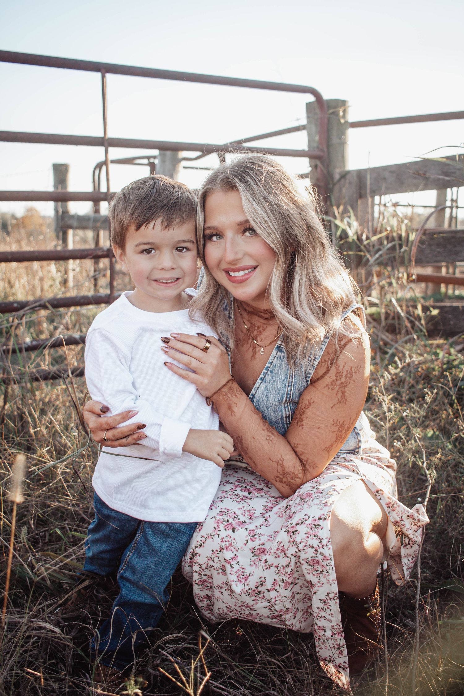 Mother and young son smiling together beside a rustic fence