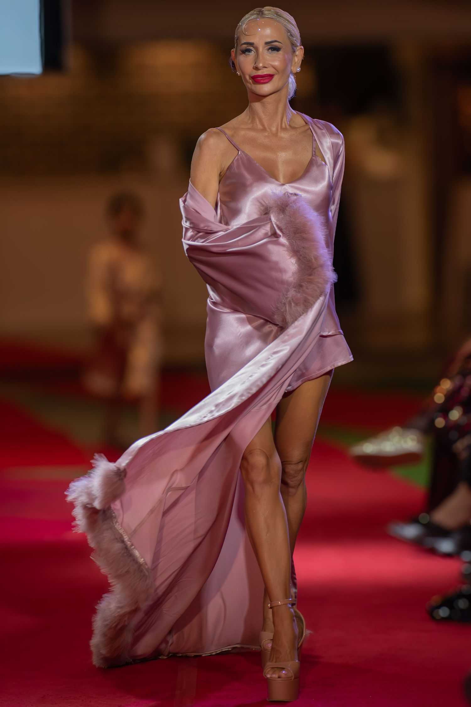Model posing at the end of a brightly lit fashion runway at a Brisbane event.
