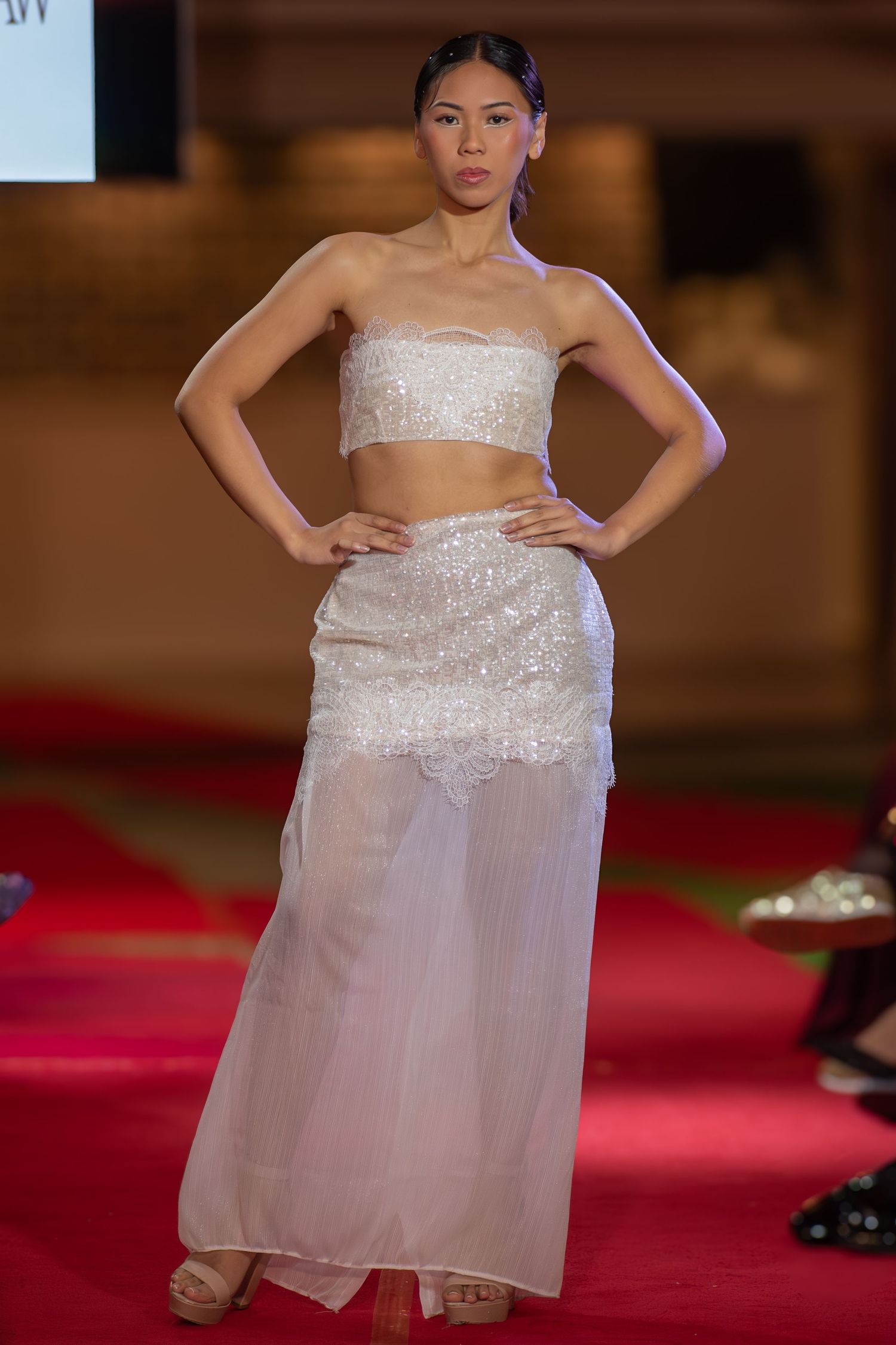 Model posing at the end of a brightly lit fashion runway at a Brisbane event.