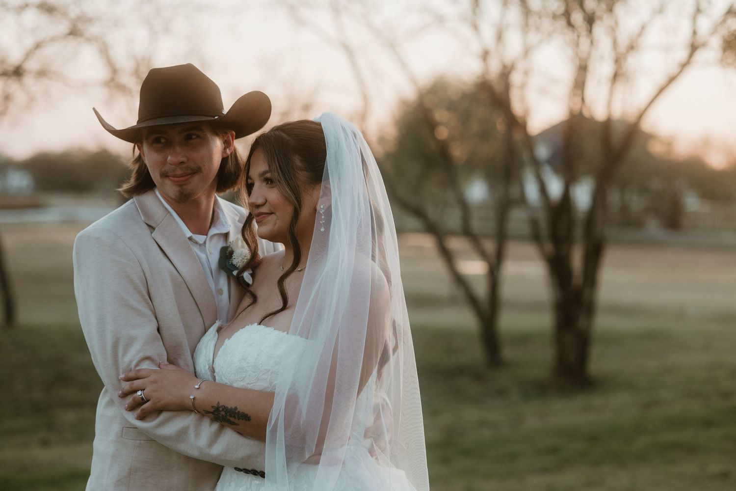 Bride and groom wrapped in each others arms. In a field at deerfield estates in central Texas.