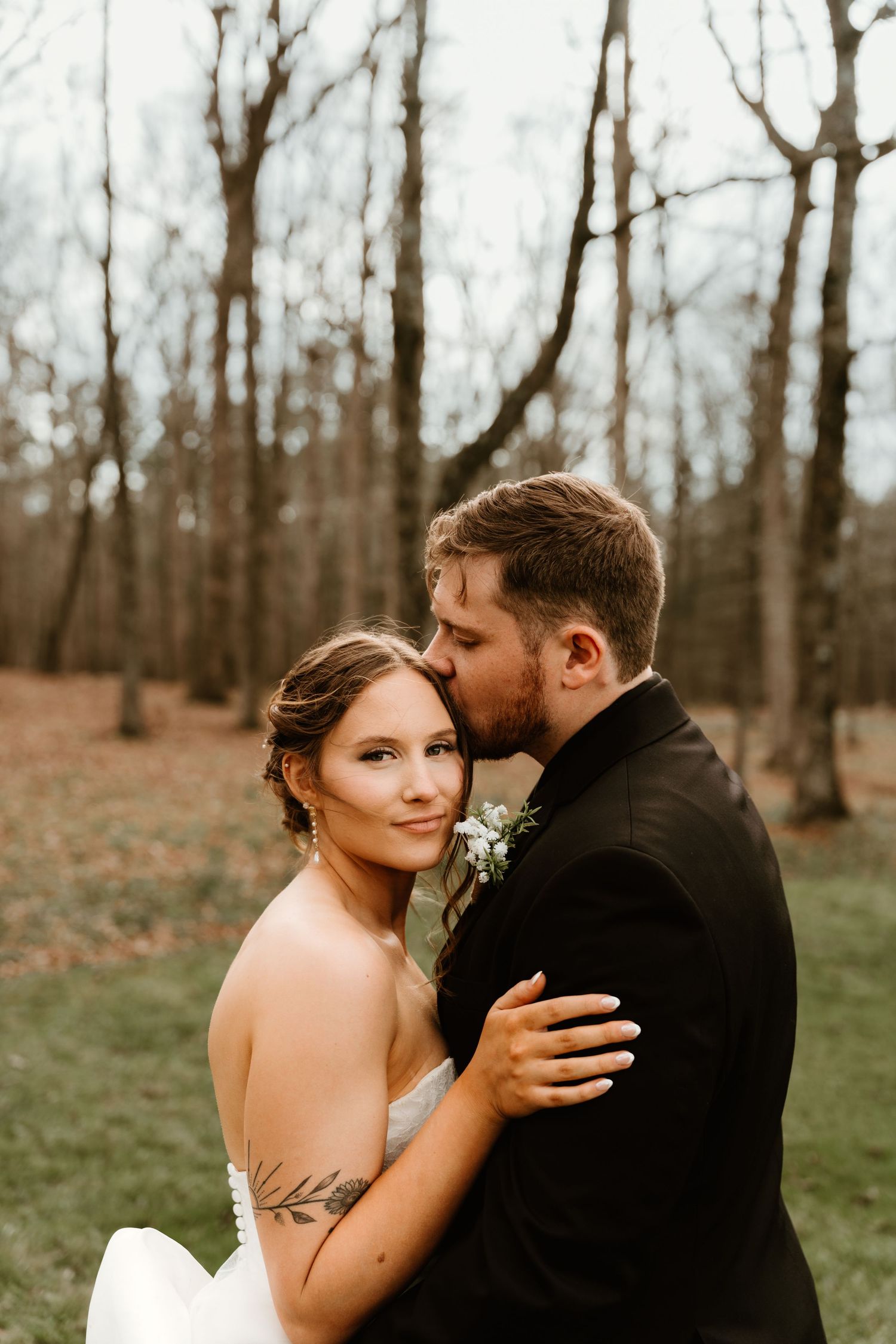 Bride and groom embracing outdoors in a wooded setting after the ceremony