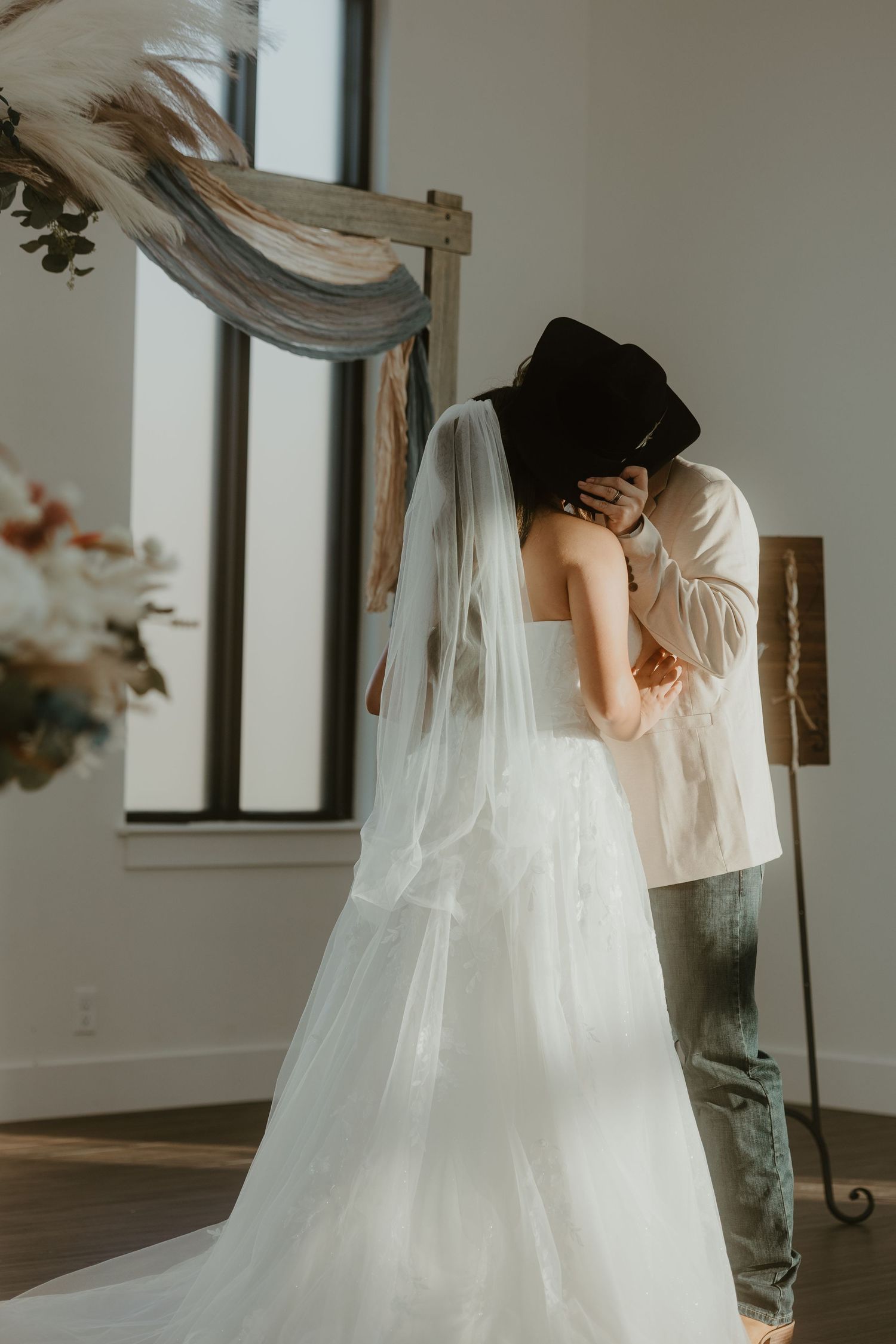 Bride and groom kissing in the deerfield estates chapel under the alter behind cowboy hat.