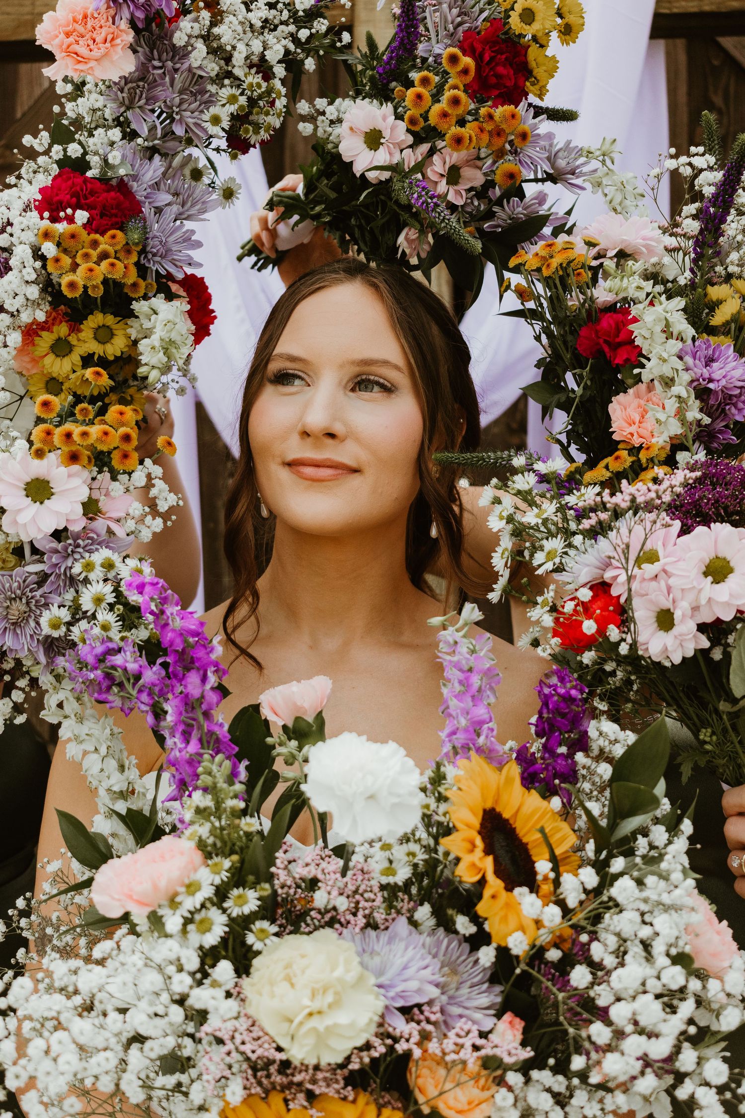 Bride holding a colorful bouquet with a floral backdrop behind her