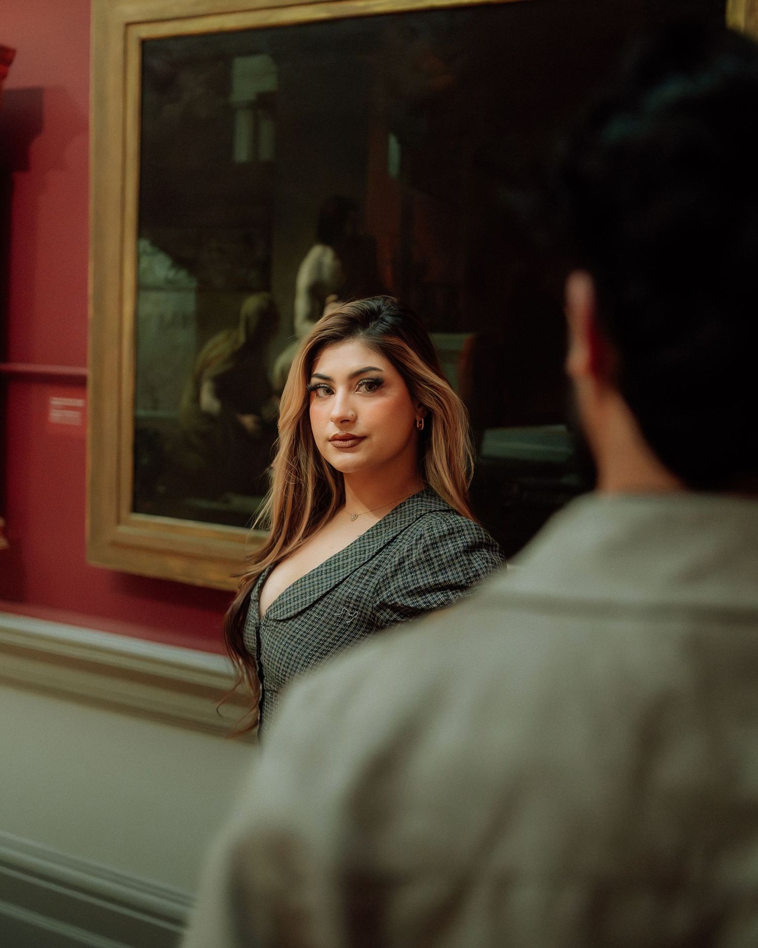 Young woman with long hair gazing at her partner inside a classic art museum.
