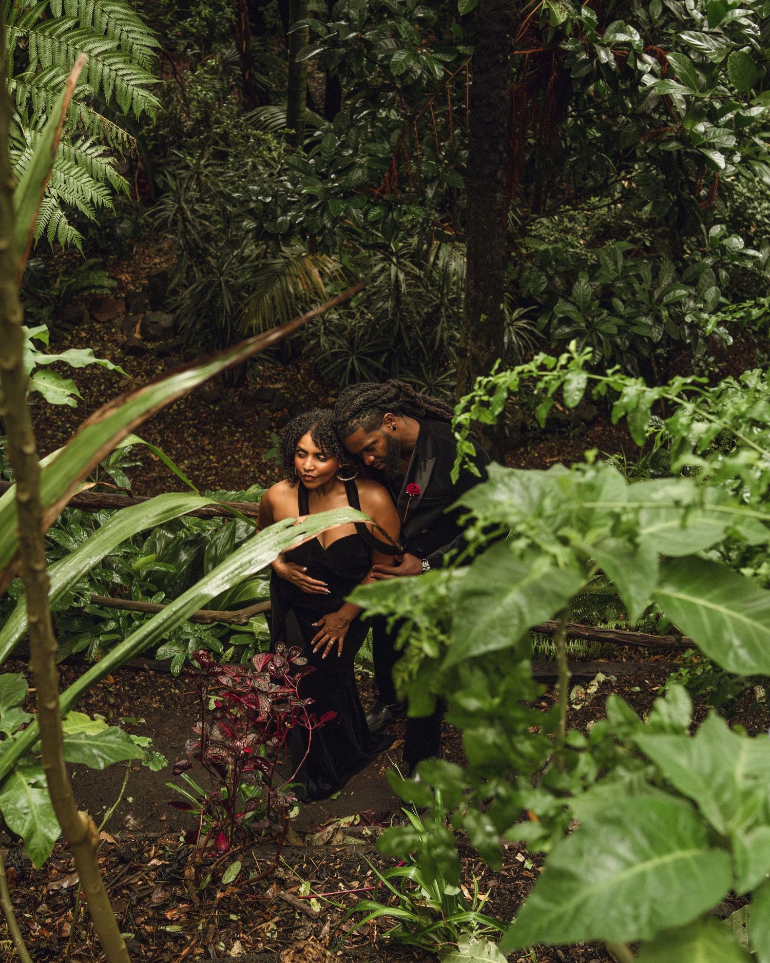 Couple sharing an intimate moment surrounded by lush tropical jungle foliage.