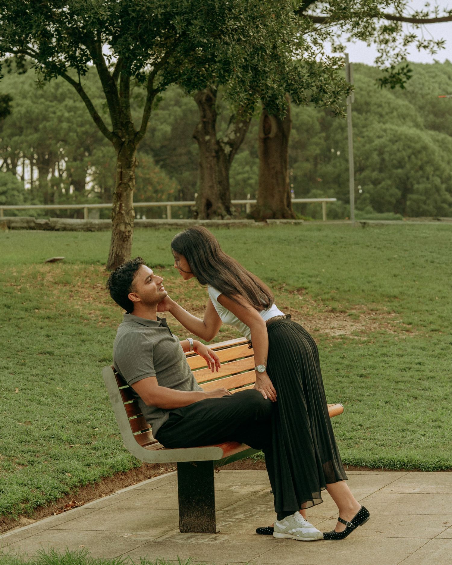 Couple sitting on a park bench sharing a tender moment outdoors.