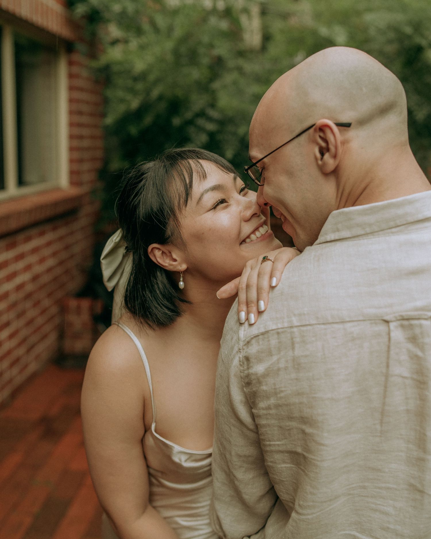 Couple sharing a joyful close moment, bride laughing with a white bow in her dark hair.