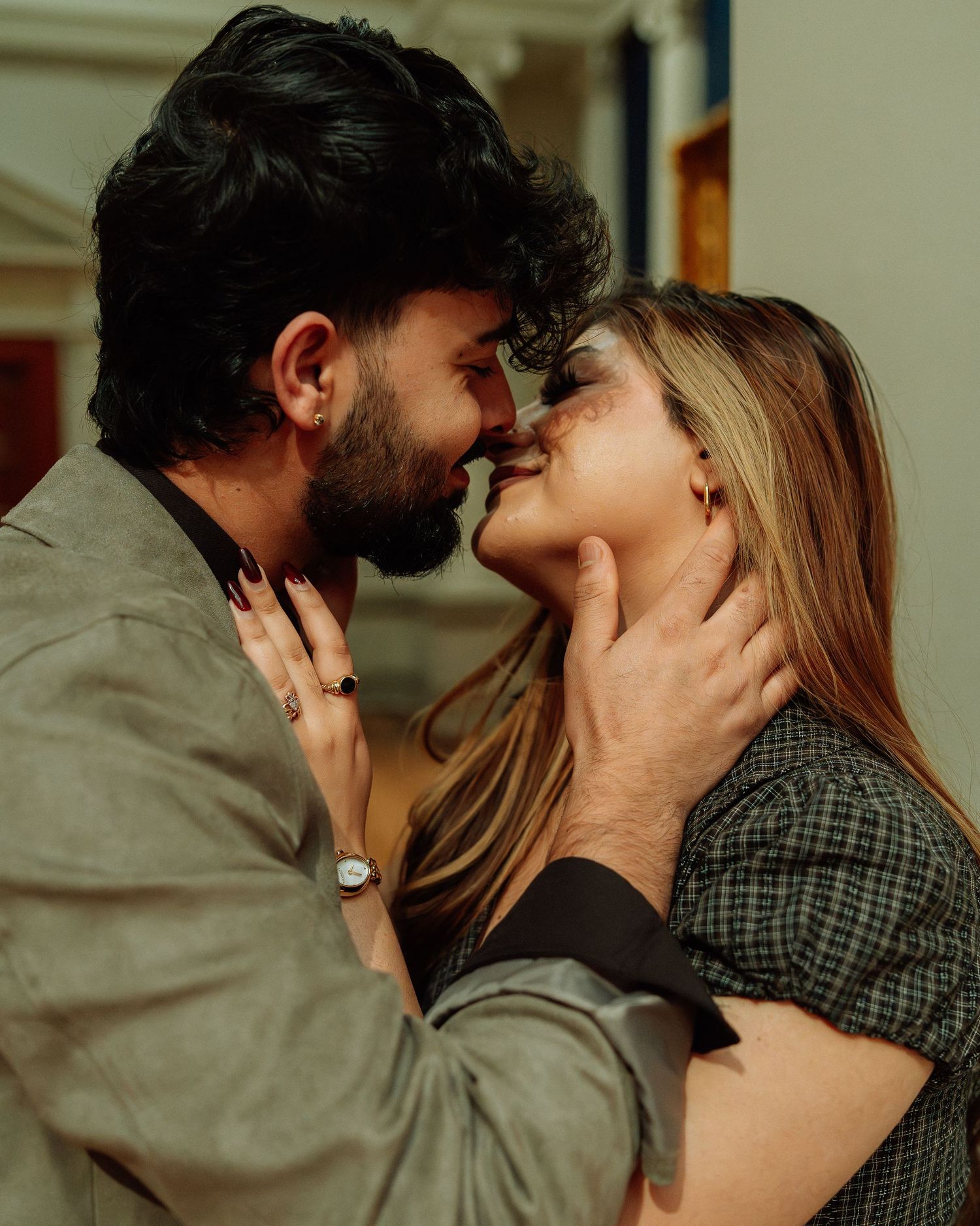 Close-up of a couple about to kiss, man gently holding womans face in warm indoor light.