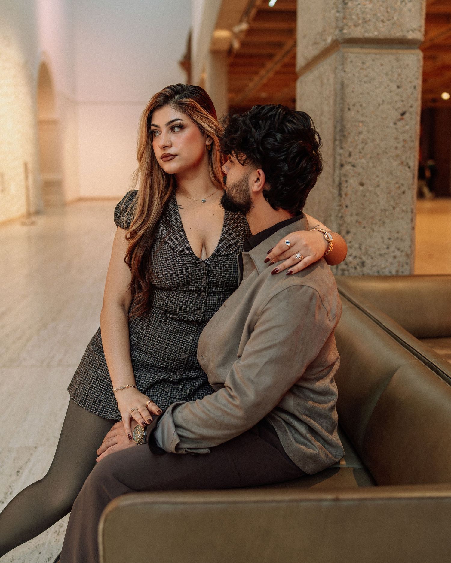 Couple sitting together on a couch in a bright modern museum interior.