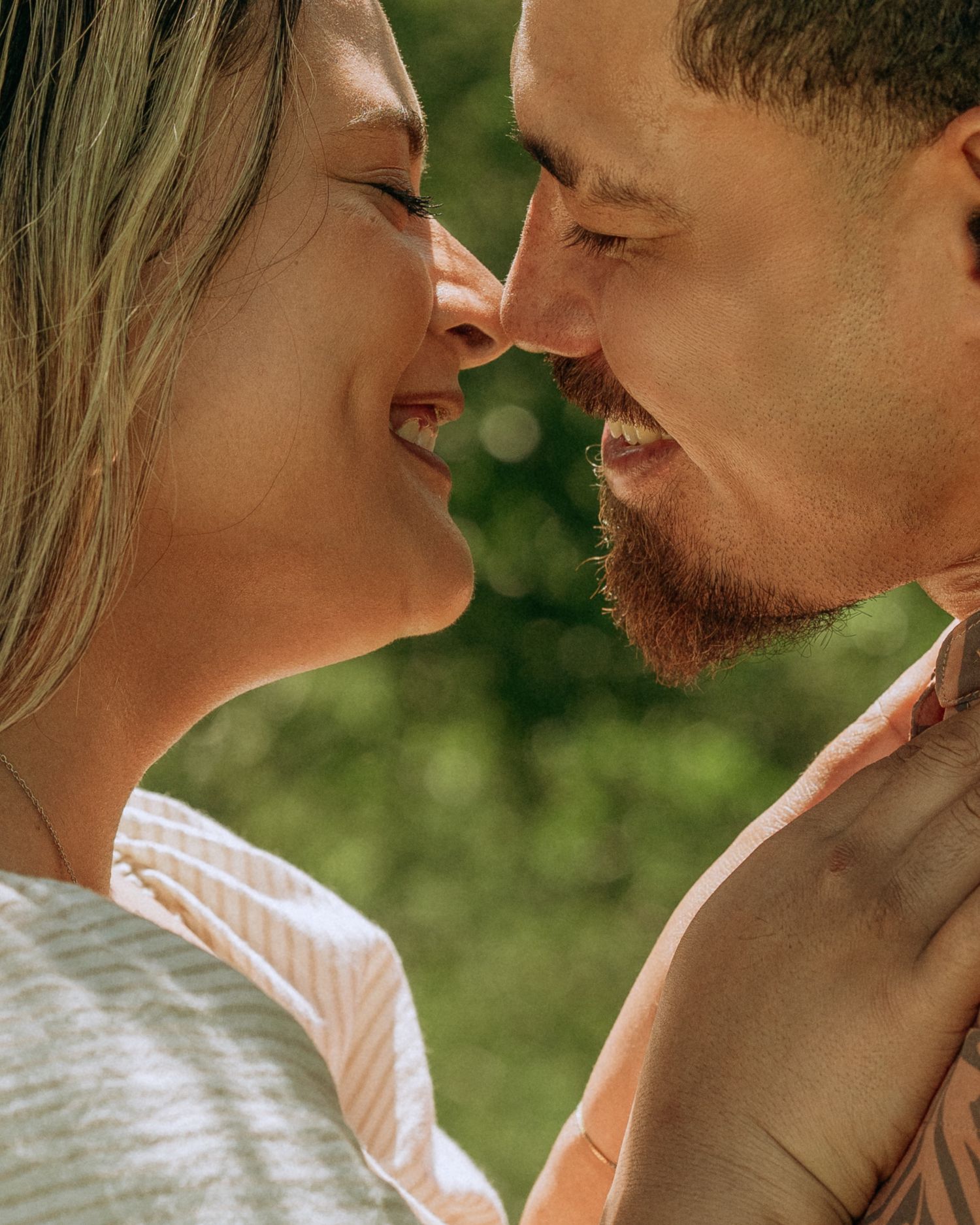 Happy couple smiling and touching noses in a close romantic outdoor portrait.