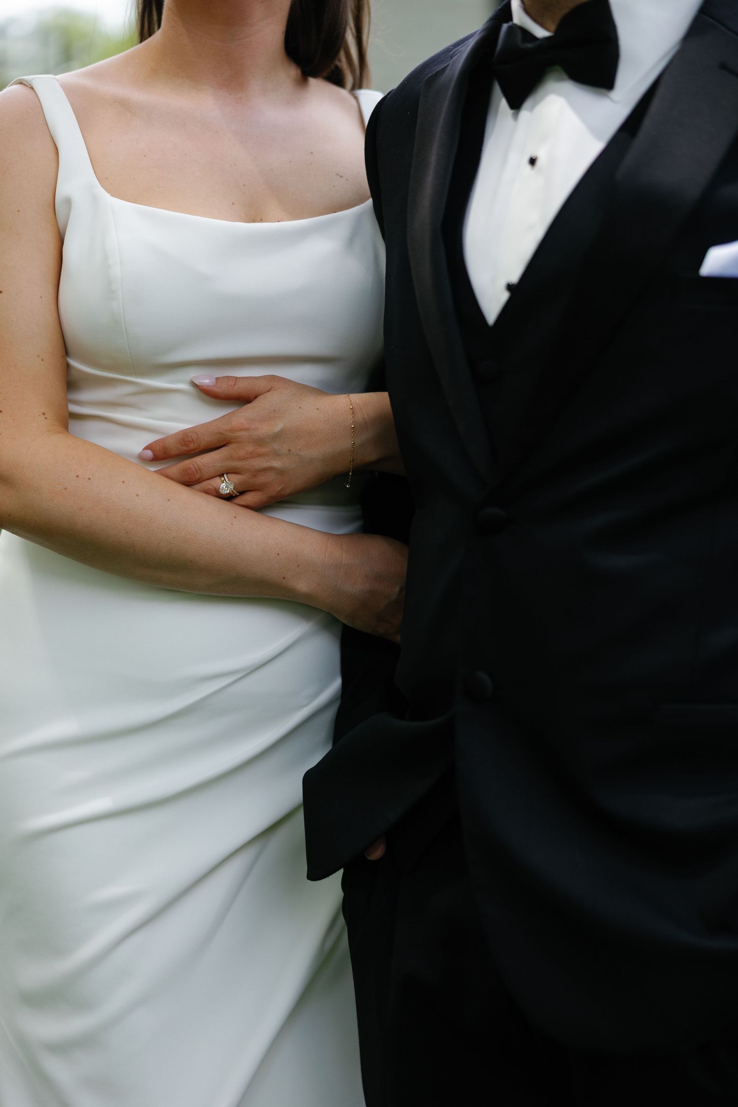 Close-up of bride in white gown and groom in black tuxedo embracing, showing diamond engagement ring. backyard wedding photographer Dayton