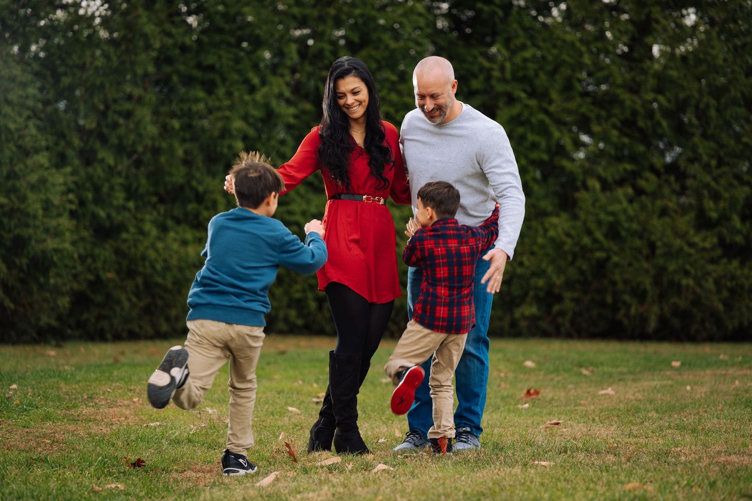 Family members enjoy playful interactions on a grassy field during autumn.