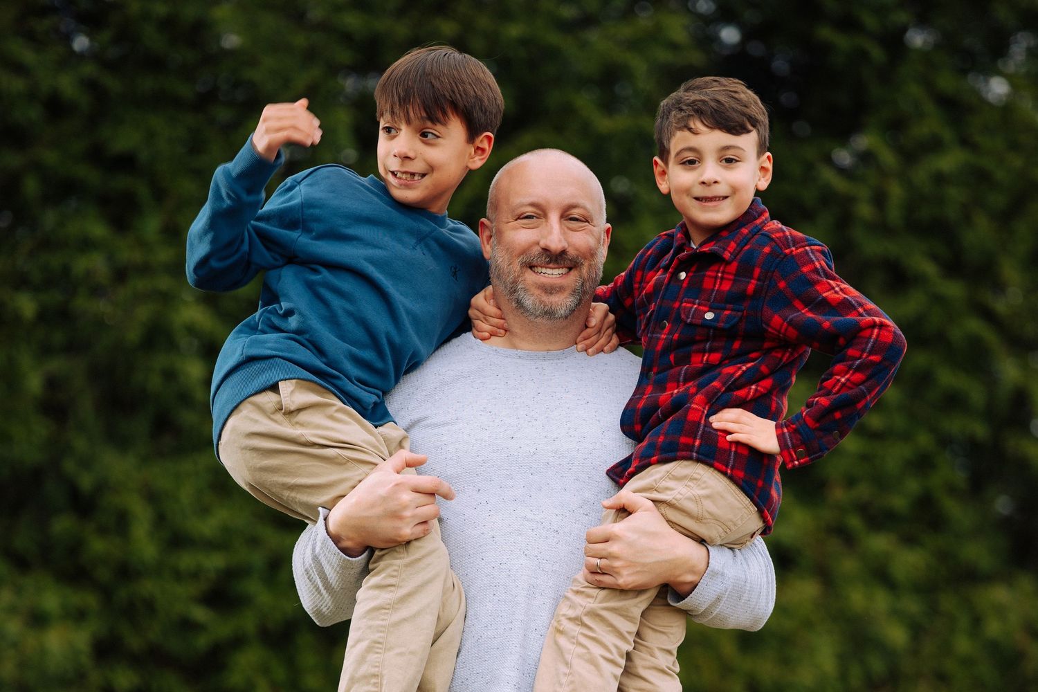 A happy family moment captured outdoors with natural foliage in the background.