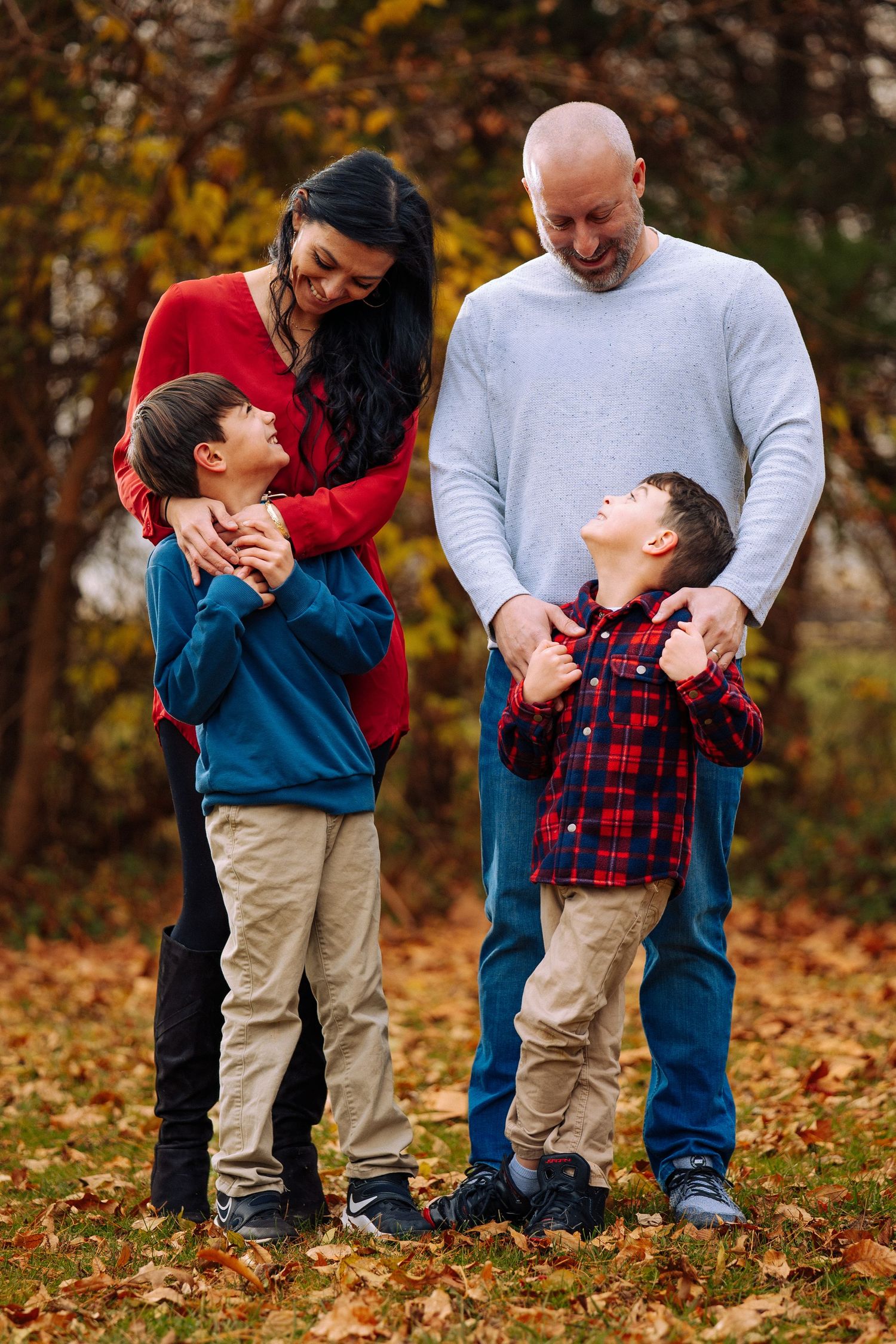 Family enjoying playful moments together on fallen autumn leaves.