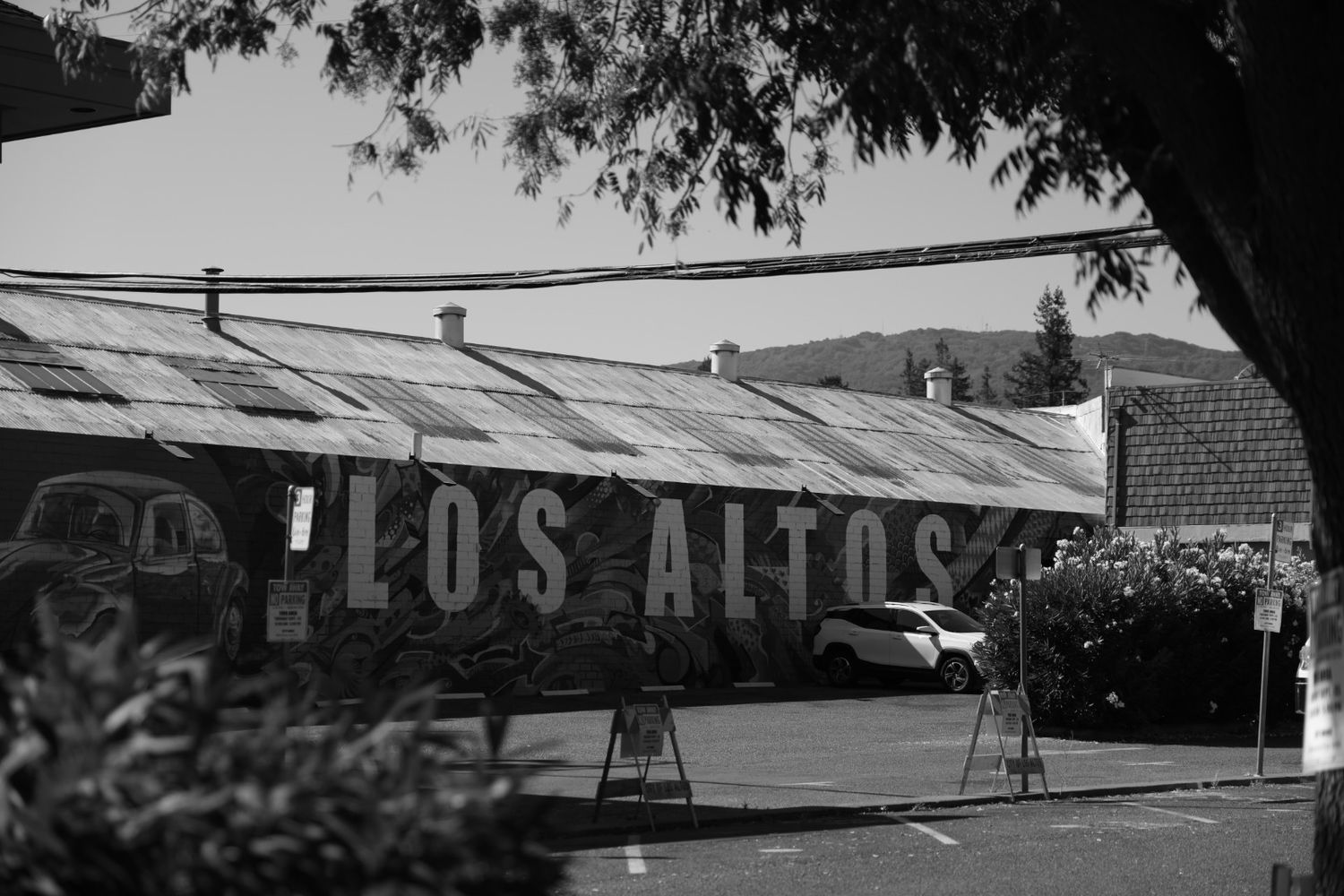 Black and white photo of Los Altos sign on a rustic building facade with mountains in the background.
