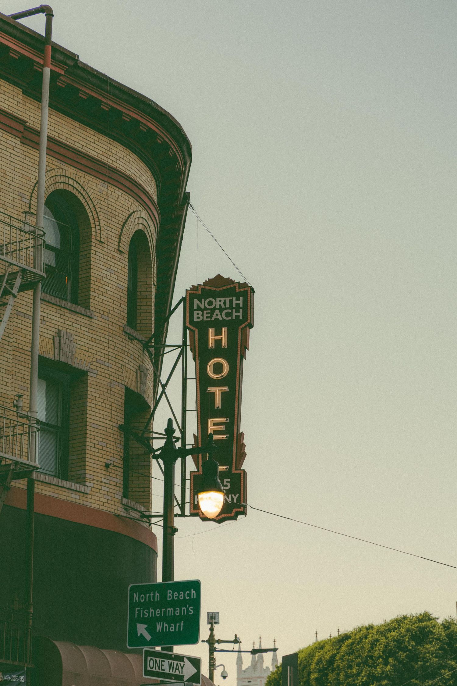 Vintage North Beach Hotel neon sign on historic brick corner building in San Francisco near Fishermans Wharf.