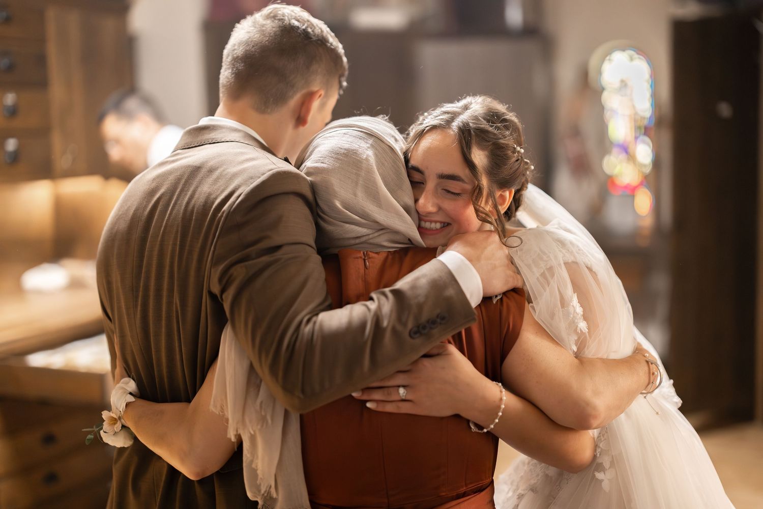 Three young people hugging with great emotion after a wedding inside a Catholic Church after a wedding in Minneapolis Saint Paul Minnesota