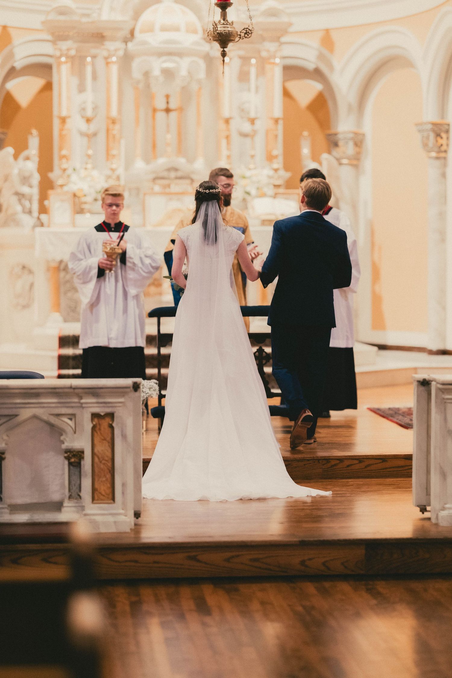 Bride and groom exchanging vows at ornate church altar during wedding ceremony.