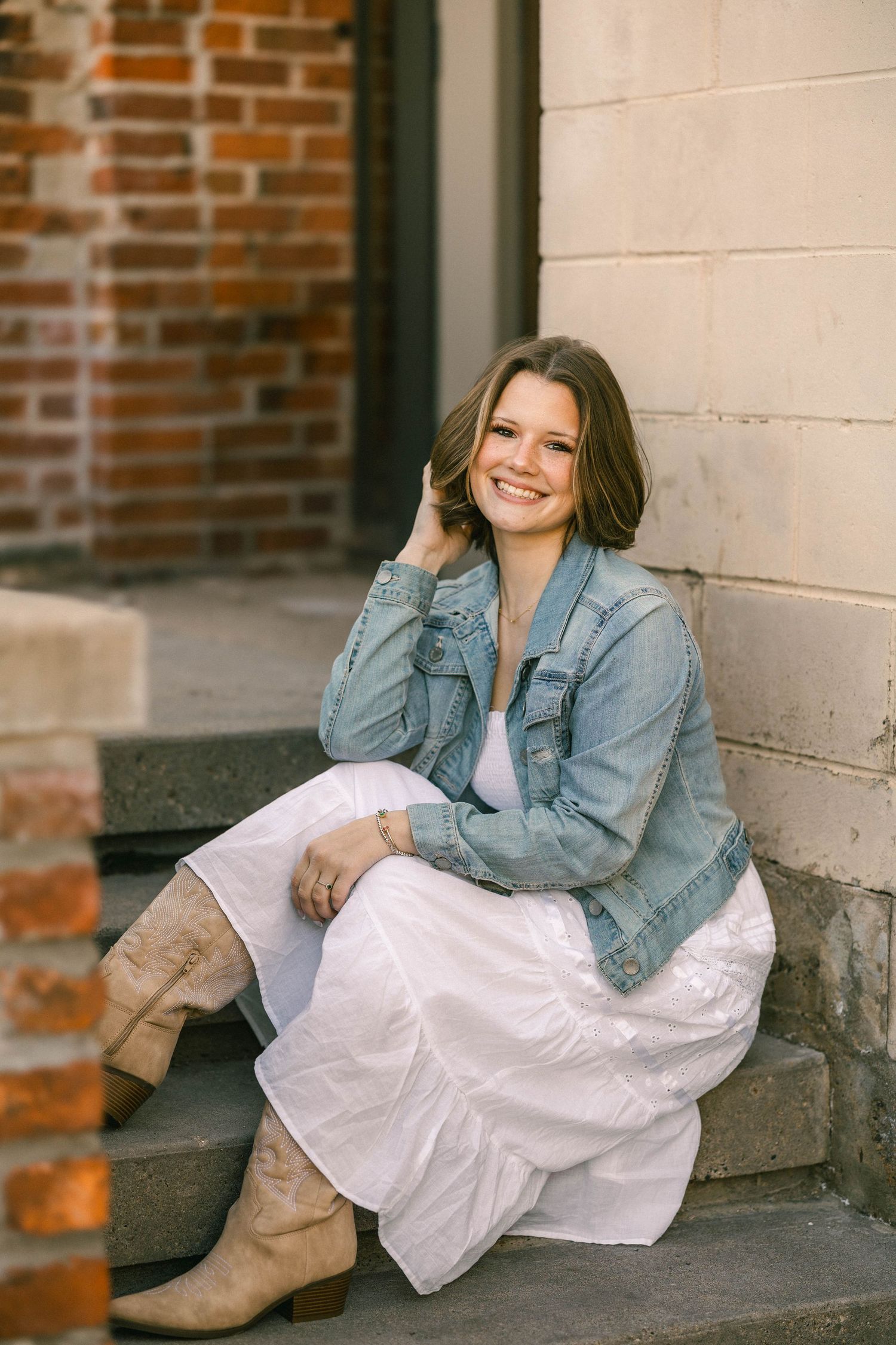 Senior portrait of a young woman seated on rustic old stairs in downtown historic Stillwater Minnesota