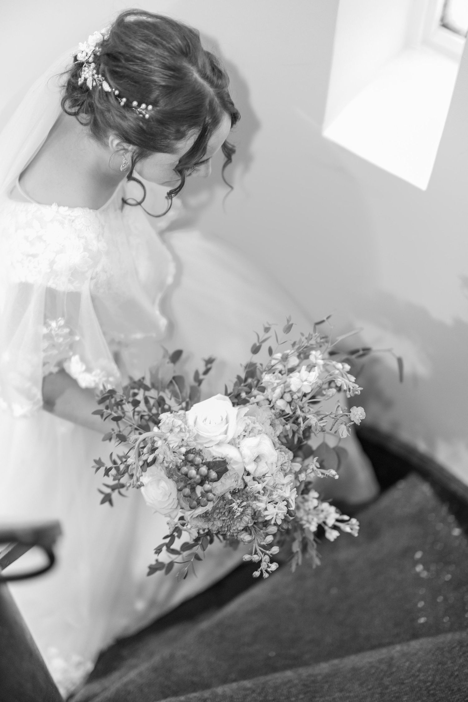 A black and White portrait of a bride walking up winding historic stairs in a Catholic Church in Minneapolis Minnesota