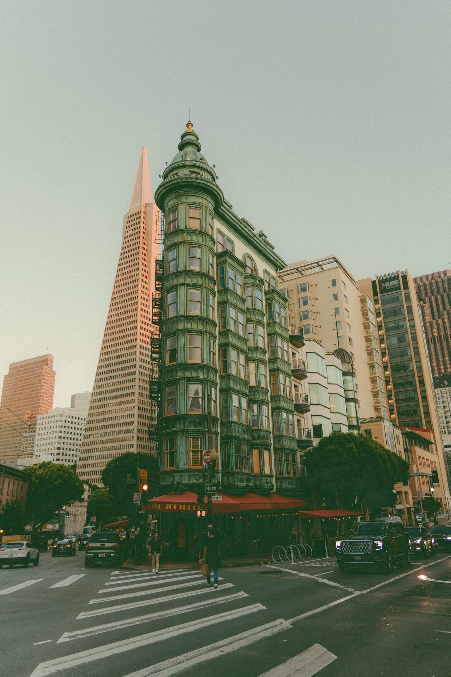 Historic green Sentinel Building with ornate dome near Transamerica Pyramid in downtown San Francisco at dusk.