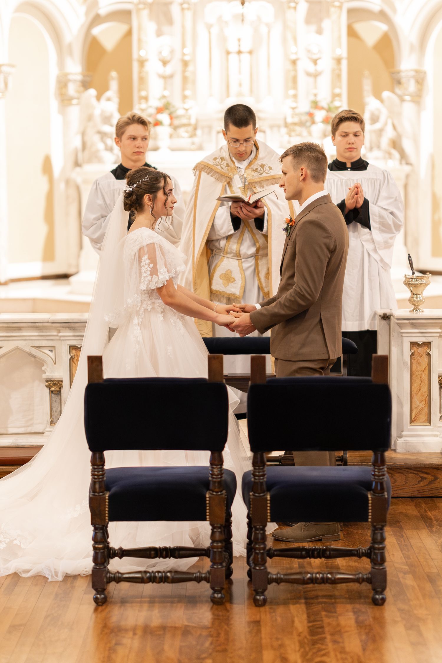Bride and groom holding hands at the altar during a Catholic church wedding ceremony.