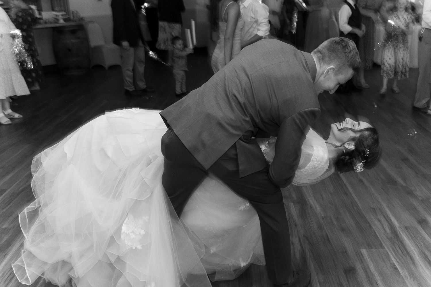 Black and white photo of bride and groom sharing a romantic dip during their first dance at the wedding reception.