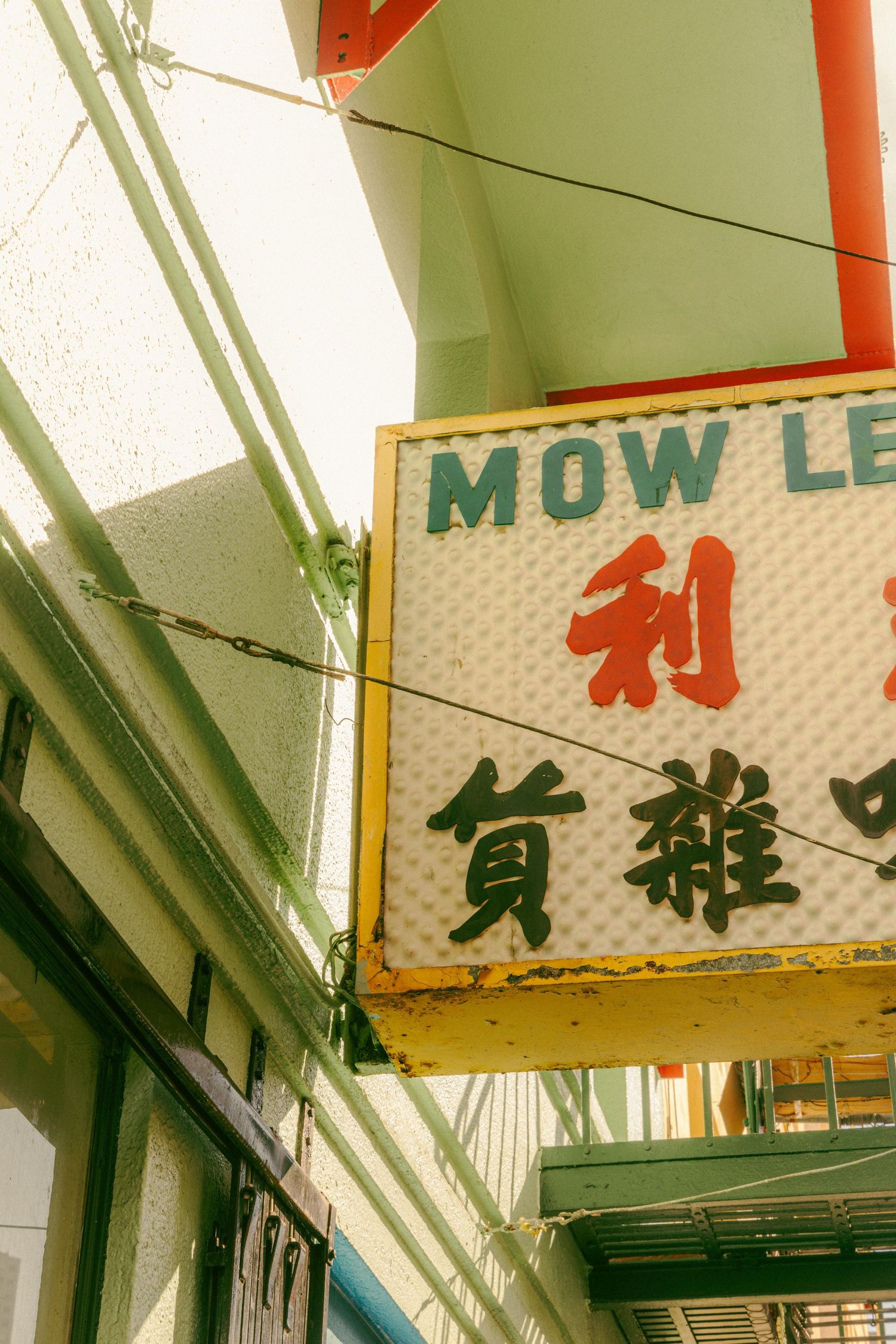 Vintage Mow Lee store sign with Chinese characters and red lettering in San Francisco Chinatown.