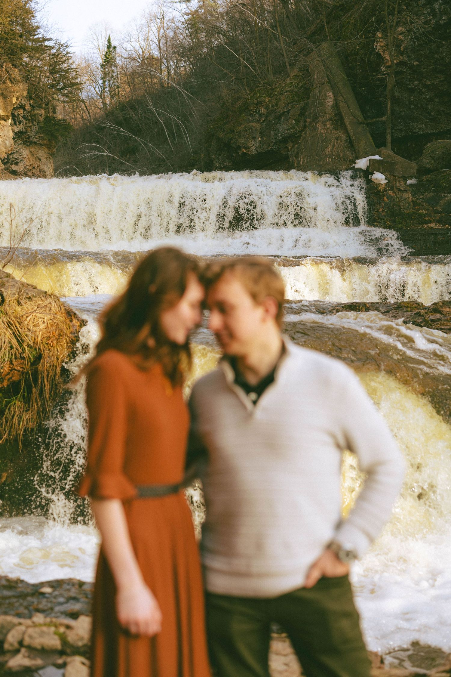 Couple touching foreheads tenderly with a rushing waterfall in the background.