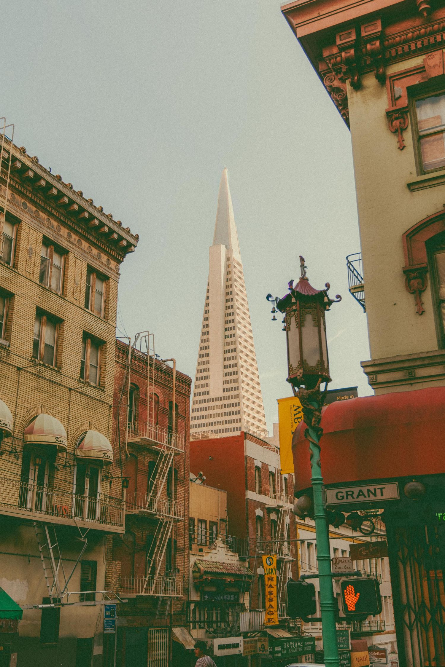 The iconic Transamerica Pyramid tower rises above historic brick buildings on Grant Avenue in San Francisco's Chinatown district.