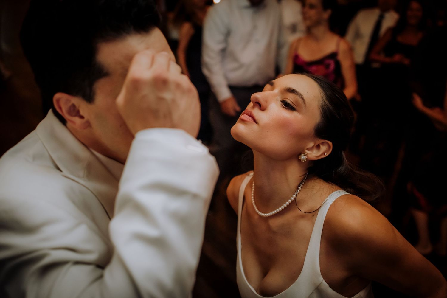 Intimate dance moment captured in dramatic lighting during wedding celebration.