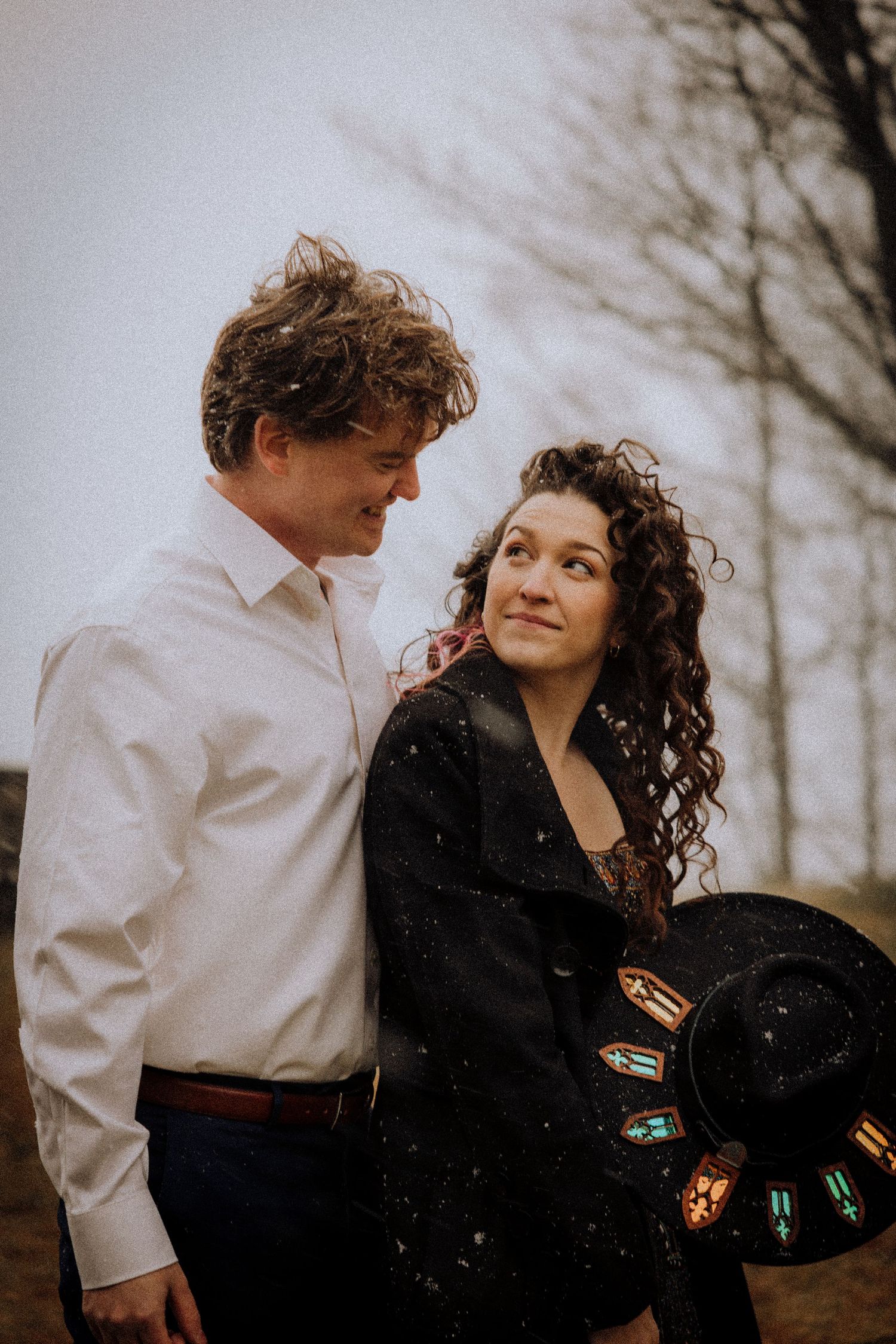 A couple shares tender moments outdoors while dressed in contrasting outfits.