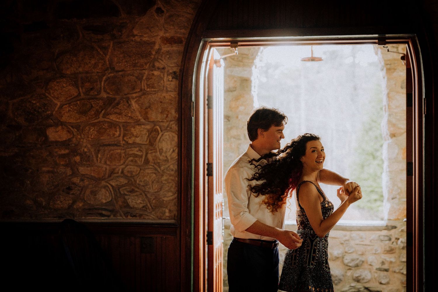 Dancing silhouettes against bright window in rustic stone room.