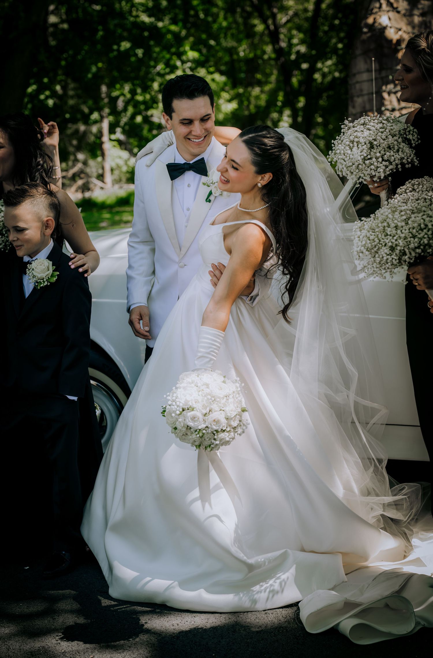 A wedding couple shares a joyful moment outdoors surrounded by baby's breath decorations.