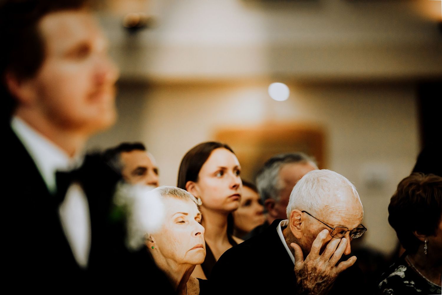 Wedding guests share emotional reactions during a ceremony in an indoor venue.Editorial and Cinematic Wedding photos