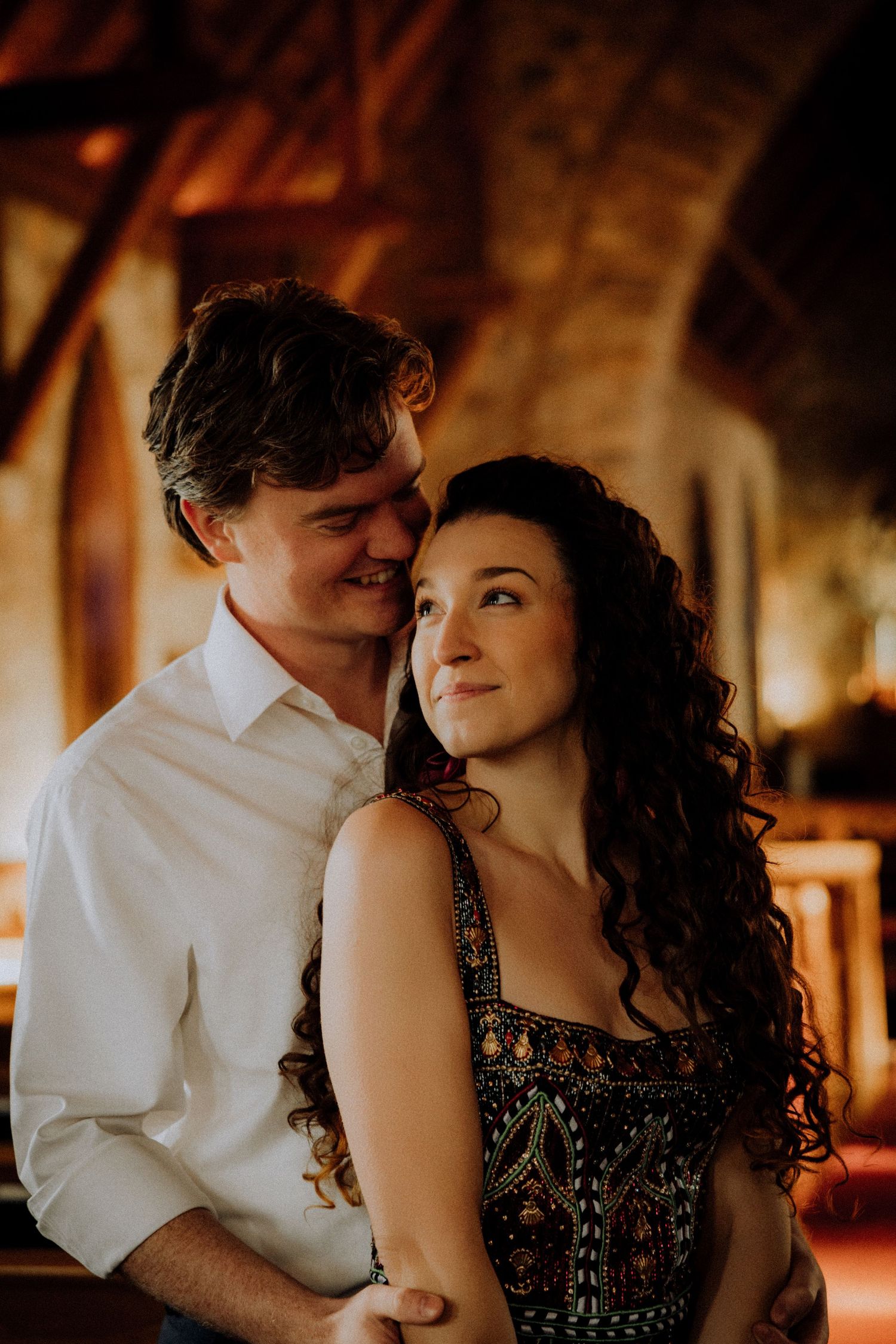Couple sharing romantic moment in vintage-style setting with warm ambient lighting.