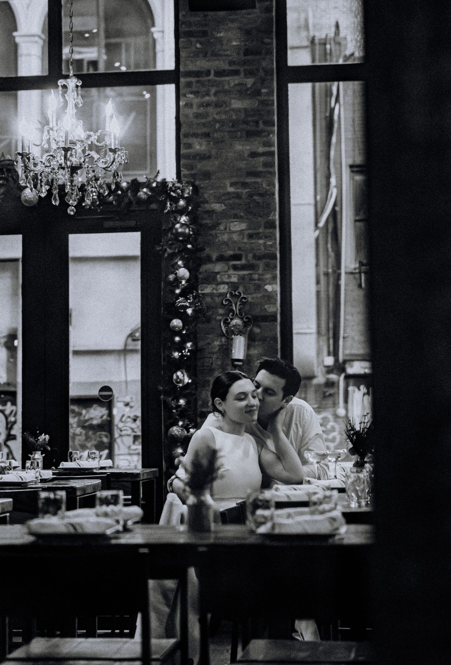 Romantic dining scene through window frames at an upscale restaurant.