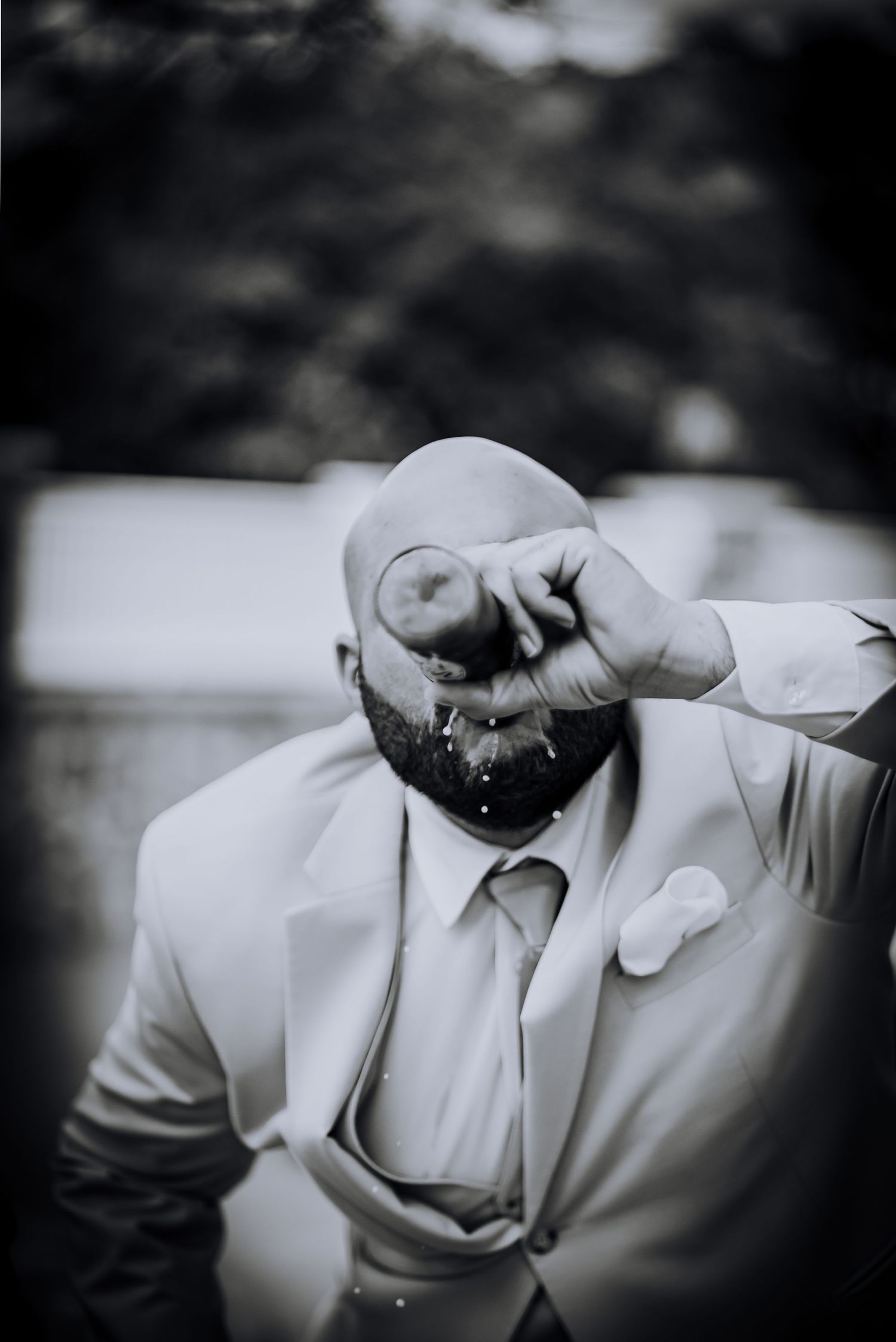 Black and white portrait of person in light colored suit splashing water in playful moment.Editorial and Cinematic Wedding photos