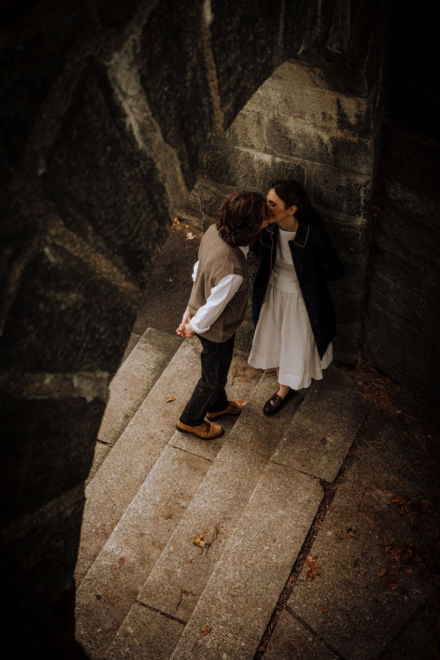 An overhead view of a couple embracing on stone steps.