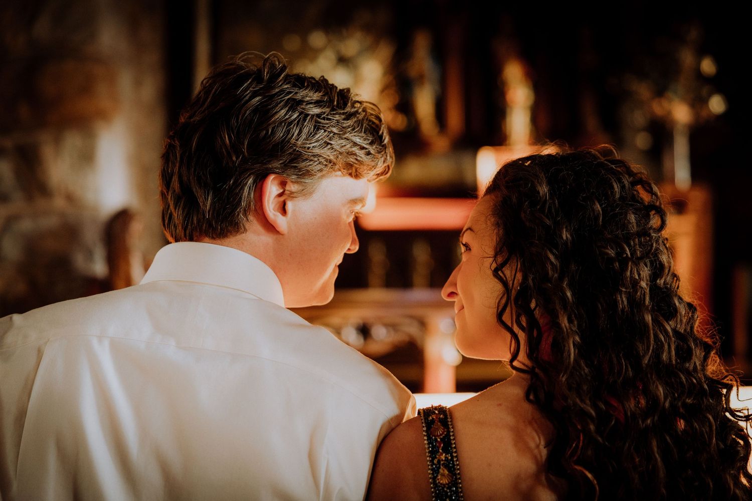 Romantic couple shares an intimate dance in warm lighting at a rustic venue.