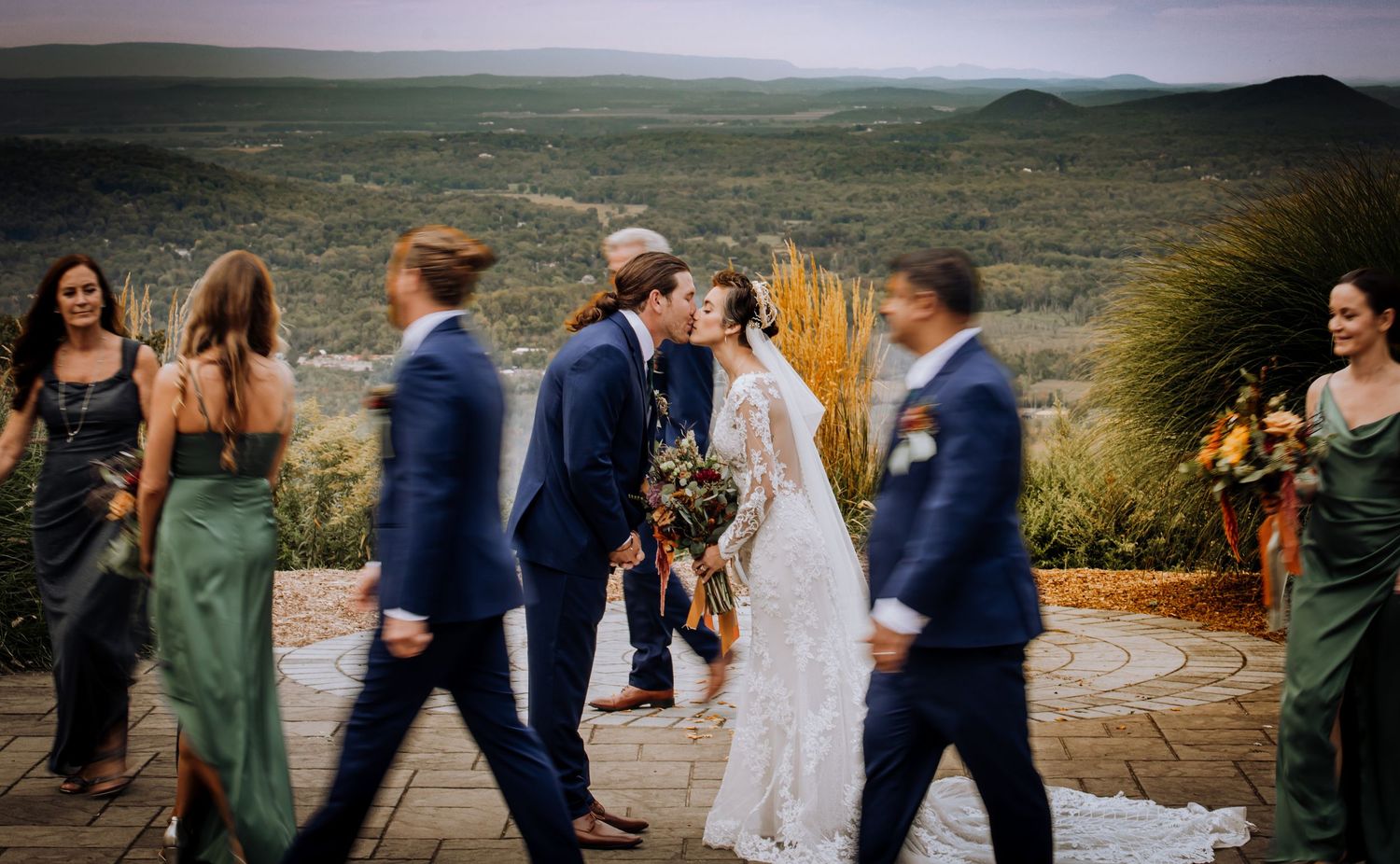 Wedding party poses outdoors with scenic mountain views in the background.
