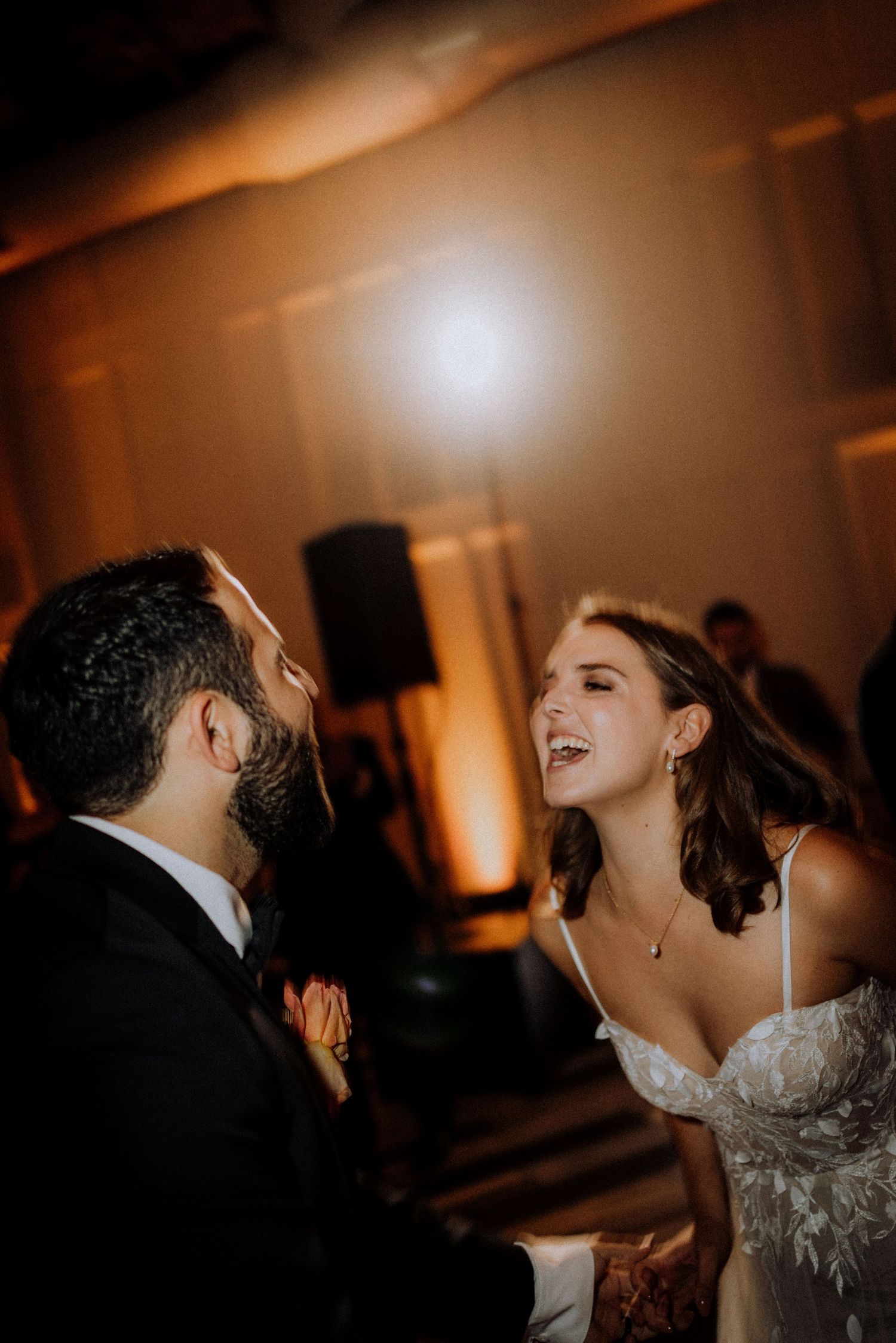 Wedding reception dance floor with couples dancing in warm ambient lighting.