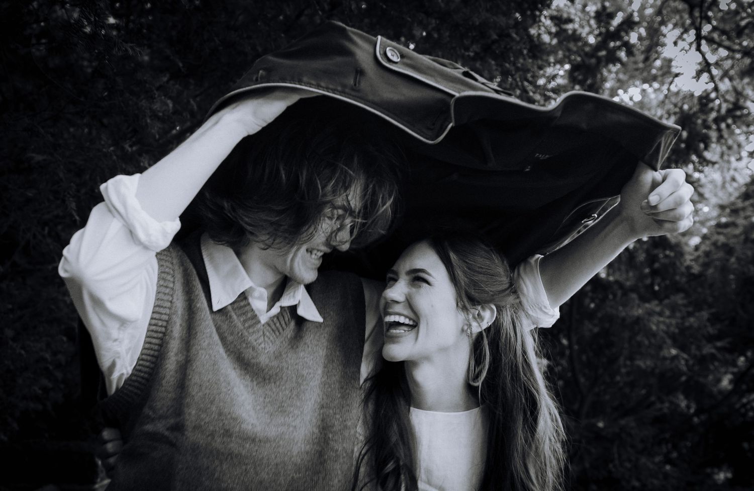 A romantic couple shares intimate moments in a moody outdoor photoshoot with dramatic lighting and natural scenery.