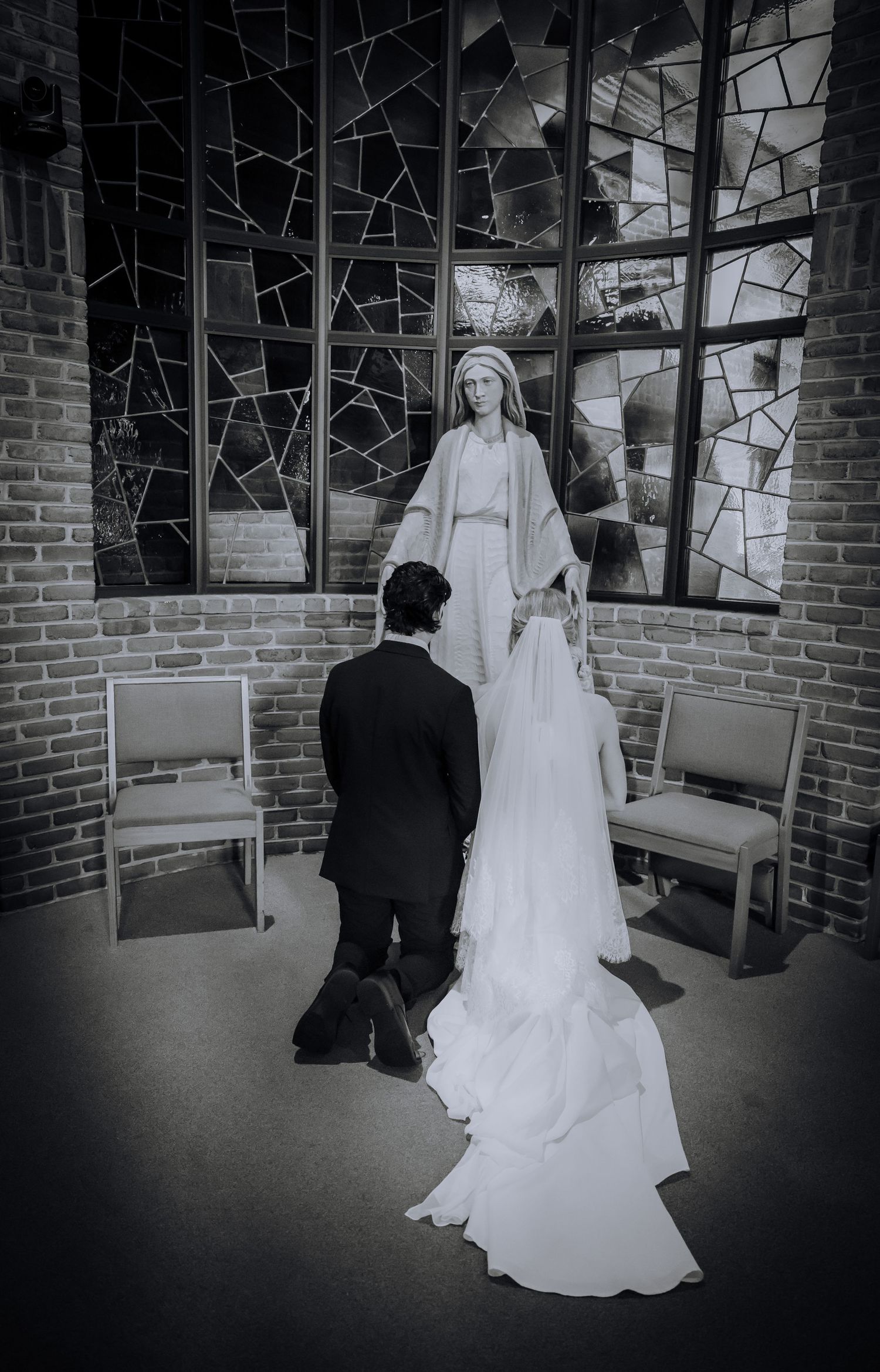 Black and white photo of a couple in a brick-walled church waiting area.