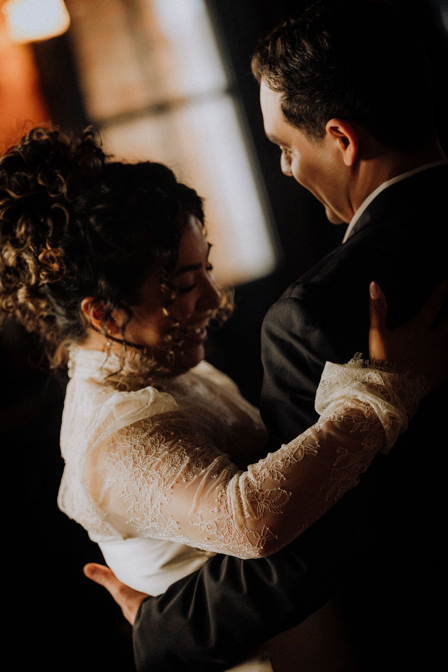 downtown-los-angeles-eA bride and groom share an intimate first dance, embracing closely in warm, moody lighting at their wedding reception.